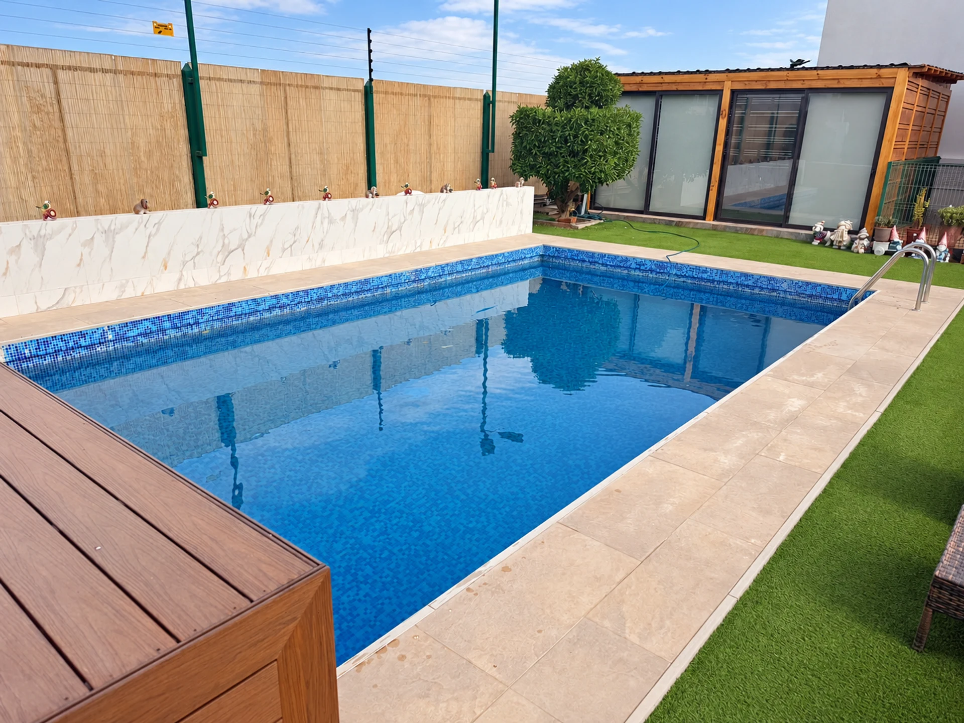 Piscina, terraza y espacio de jardín en un proyecto residencial, con terminaciones de madera